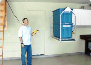 A man using an attic lift with two blue totes on it.